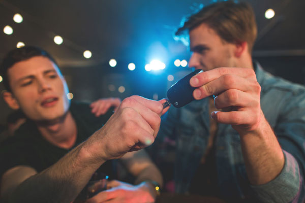 two guys at a bar with one taking the keys away from him so he does not drive